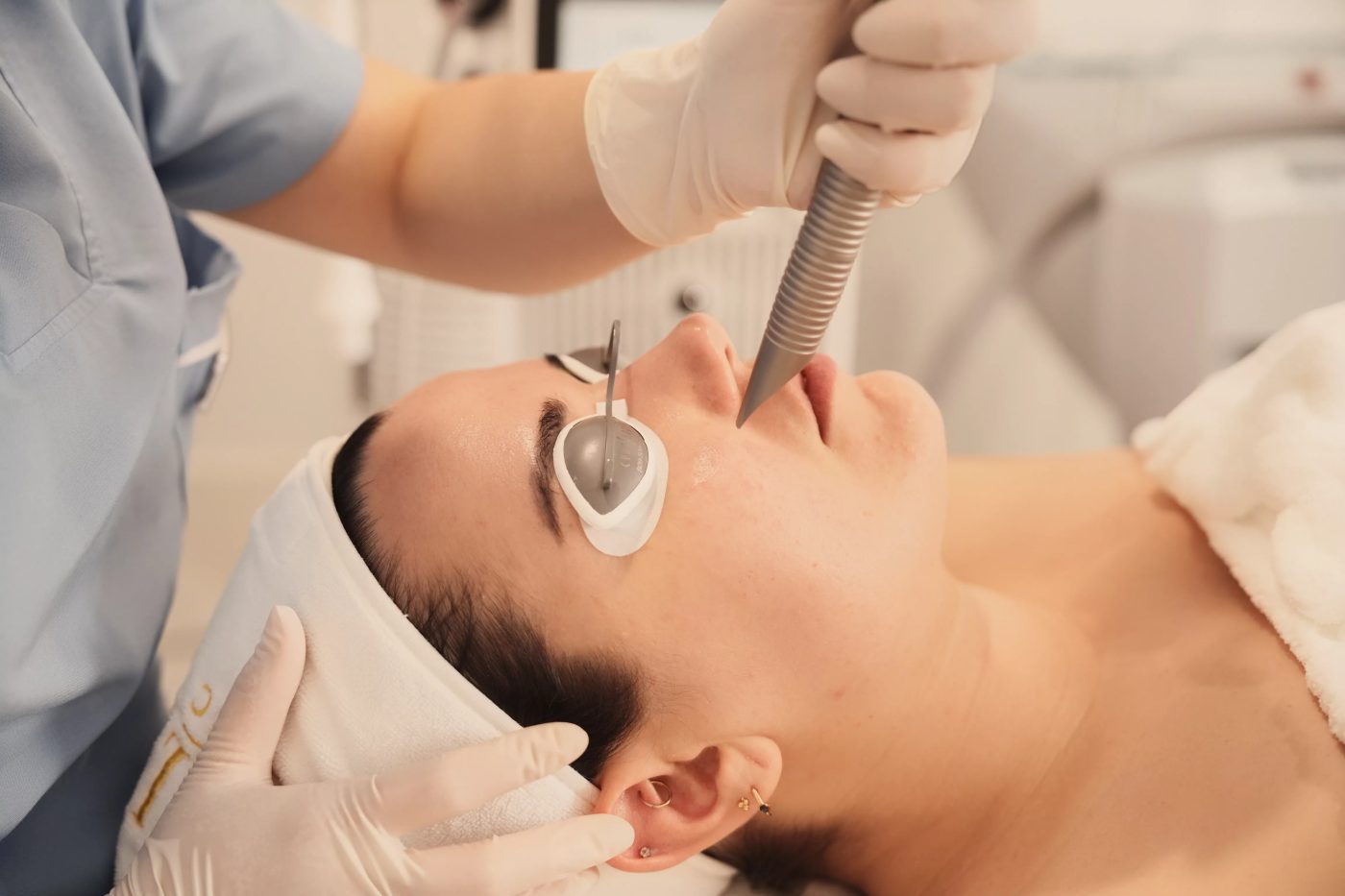 Fotona 4D facial laser procedure with protective eye shields and an external laser handpiece.